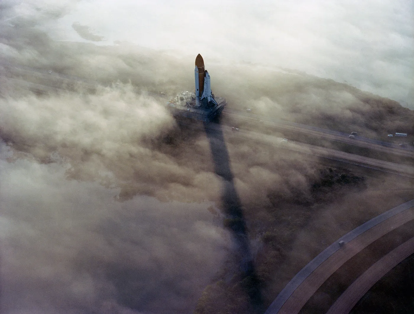 (November 30, 1982) The Space Shuttle Challenger rolls out to Pad 39A in the morning fog in this picture taken before the STS-6 mission began. This…