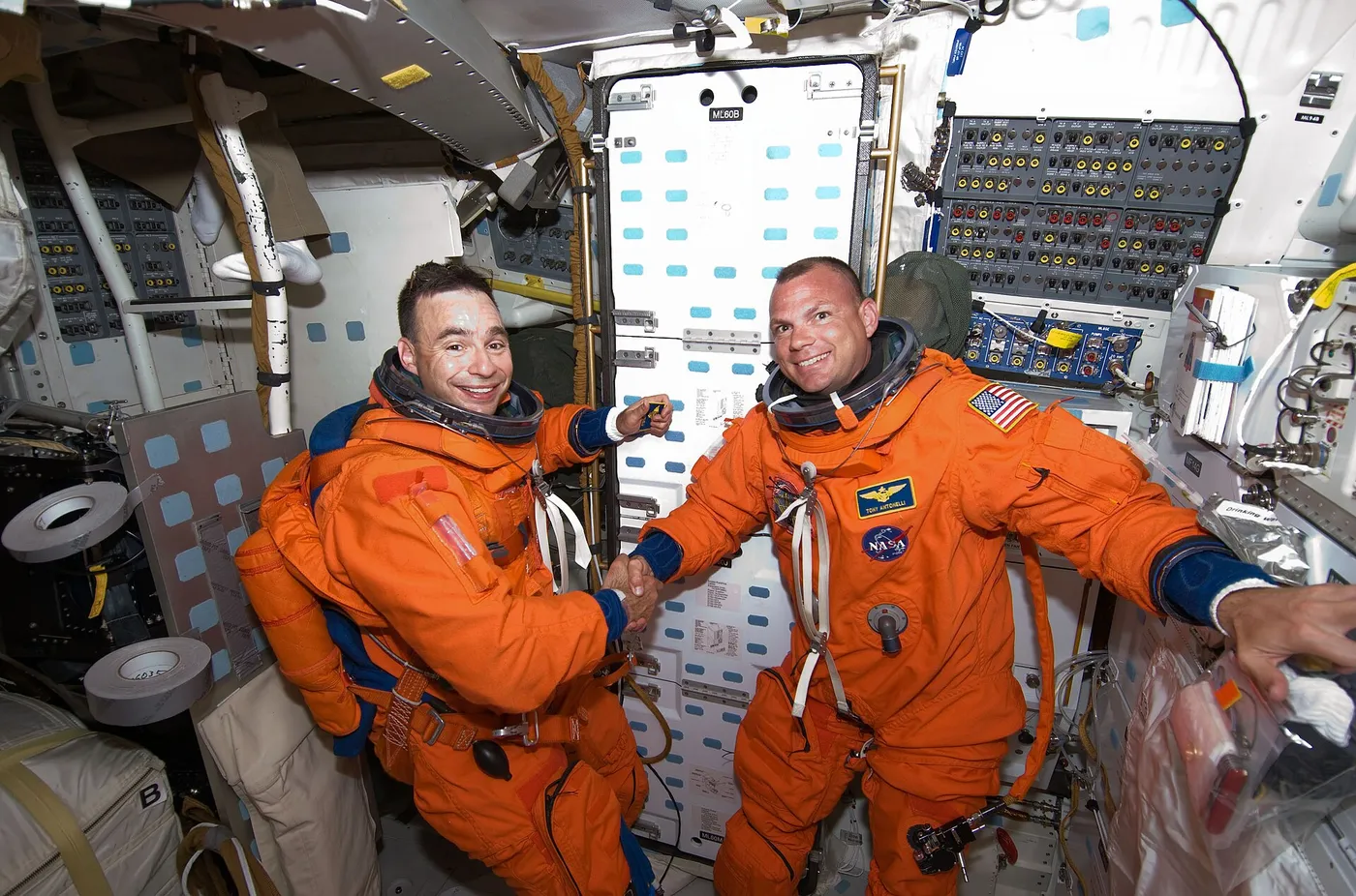 Attired in their shuttle launch and entry suits, astronauts Lee Archambault (left), STS-119 commander; and Tony Antonelli, pilot, shake hands on the…