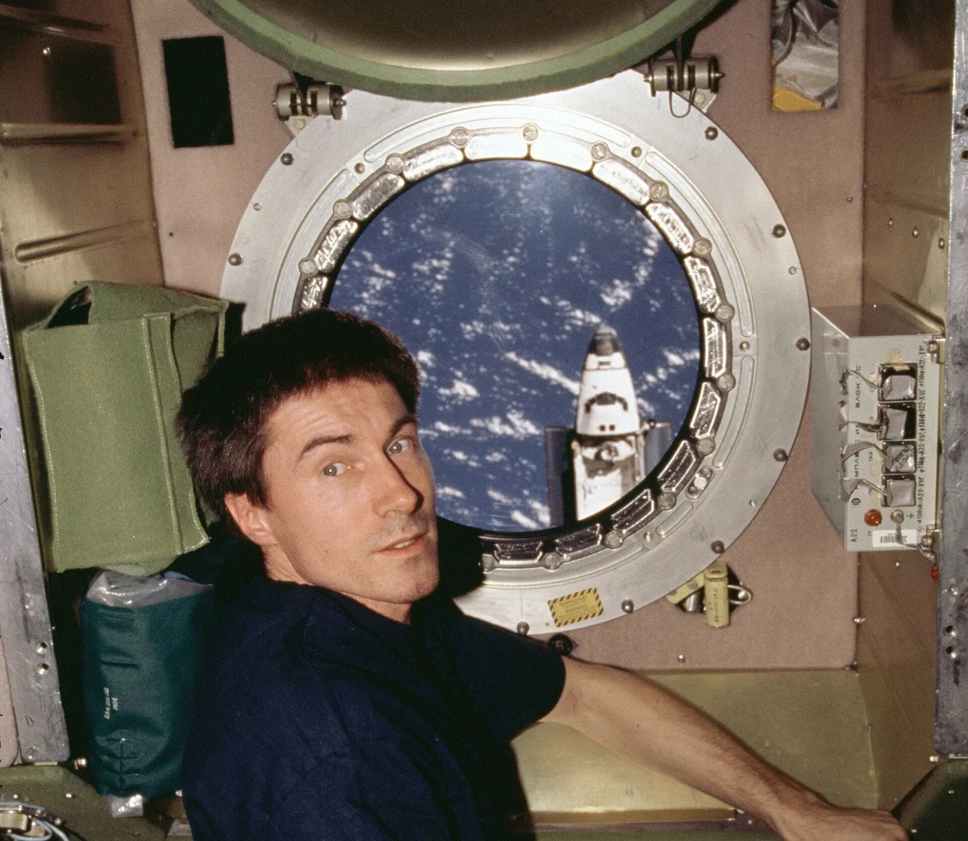 Cosmonaut Sergei K. Krikalev, flight engineer for Expedition One, is positioned at a port hole on the Zvezda service module of the International…