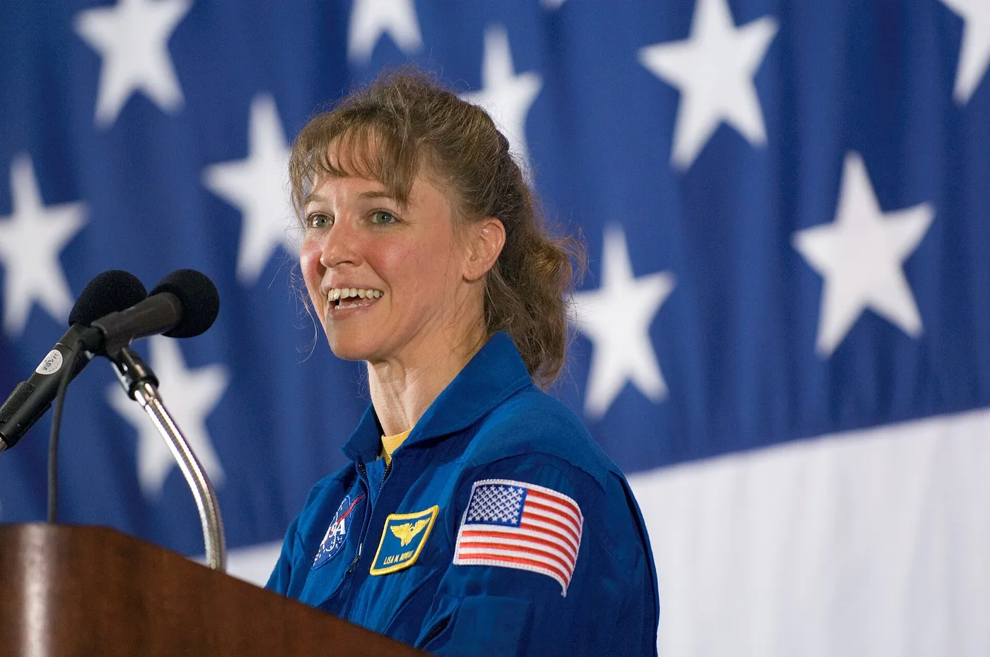JSC2006-E-28451 (18 July 2006) --- Astronaut Lisa M. Nowak, STS-121 mission specialist, speaks from a lectern in Ellington Field's Hangar 276 near…