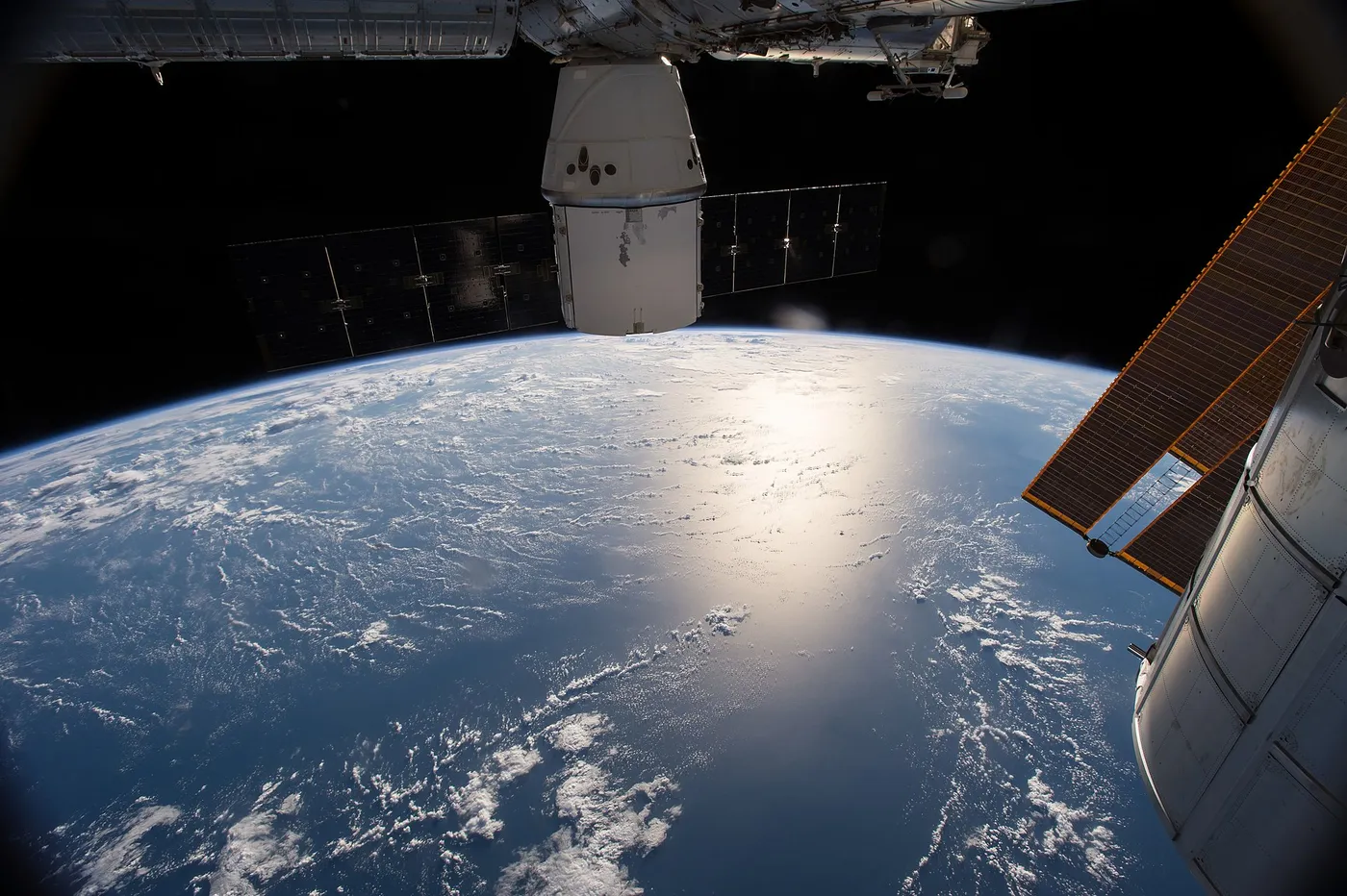 This view of Earth from the International Space Station features station modules and the CRS-6 Dragon spacecraft in the foreground.