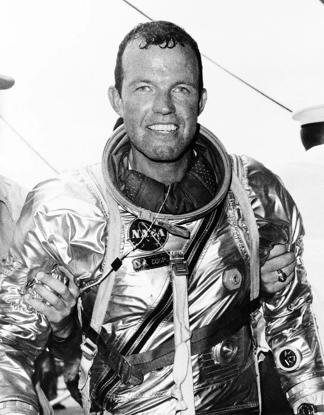Astronaut L. Gordon Cooper Jr. stands supported by strong hands after climbing out of his spacecraft Faith 7