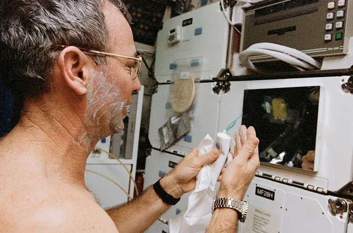 STS 72 Astronaut Brian Duffy shaves in the middeck