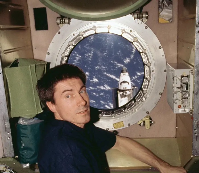 Cosmonaut Sergei K. Krikalev, flight engineer for Expedition One, is positioned at a port hole on the Zvezda service module of the International…