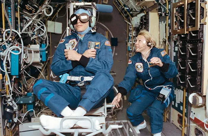 STS-58 Payload Commander Rhea Seddon spins the Spacelab Life Sciences rotating chair as Payload Specialist Martin Fettman serves as a test subject…