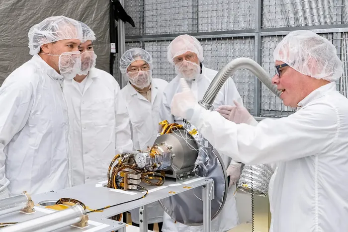 U.S. and Japanese team members gather around and discuss the gamma-ray spectrometer portion of the MEGANE instrument during its development at Johns…
