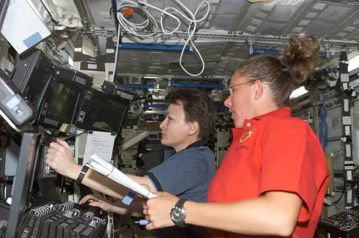 Whitson and Magnus operate the controls of Canadarm 2