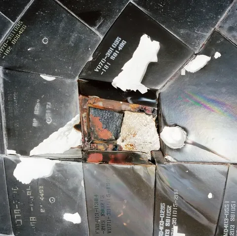 Partially melted steel mounting plate for the L-band antenna due to thermal protection tile loss in STS-27
