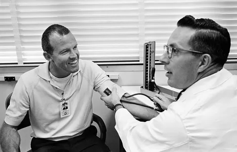 Astronaut L. Gordon Cooper Jr. has his blood pressure checked by Dr. Charles A. Berry