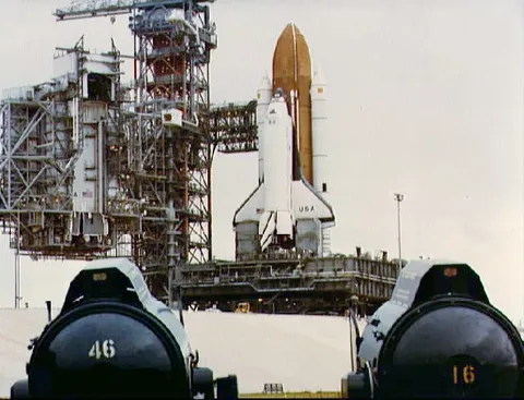 Columbia sitting on Pad 39A, following rollout for STS-4. Two spotlights in the foreground frame this daylight scence of the Columbia (32170).