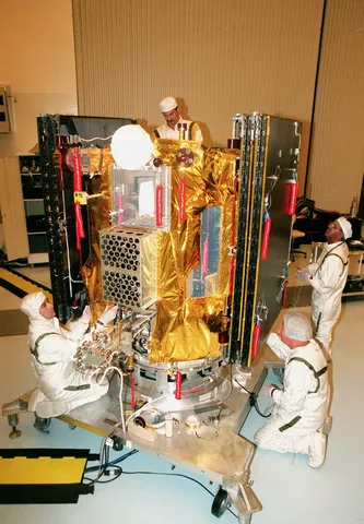 Workers in the Payload Hazardous Servicing Facility finish installing blanket insulation on Deep Space 1.