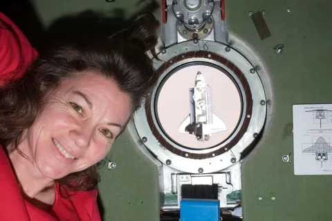ISS 27 Cady Coleman next to a porthole with the Endeavour