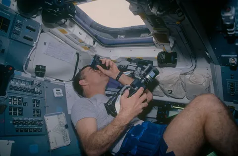 12 024 Crewmember in the aft FD photographing the Earth. DPLA 5672864c7e04d69ea987b74973ecc31d