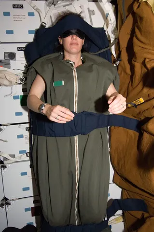 Astronaut Megan McArthur, STS-125 mission specialist, rests in her sleeping bag, which is attached to the lockers on the middeck of the…
