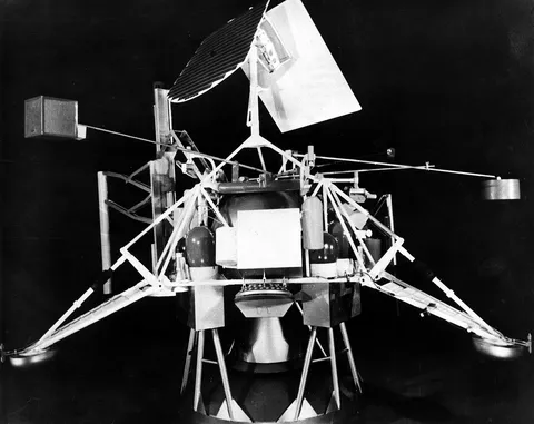 Artist's concept of a Surveyor satellite. The Atomic Energy Commission is developing an isotopic power source, designated SNAP-11, for use in the…