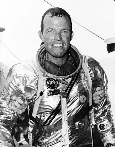 Astronaut L. Gordon Cooper Jr. stands supported by strong hands after climbing out of his spacecraft Faith 7